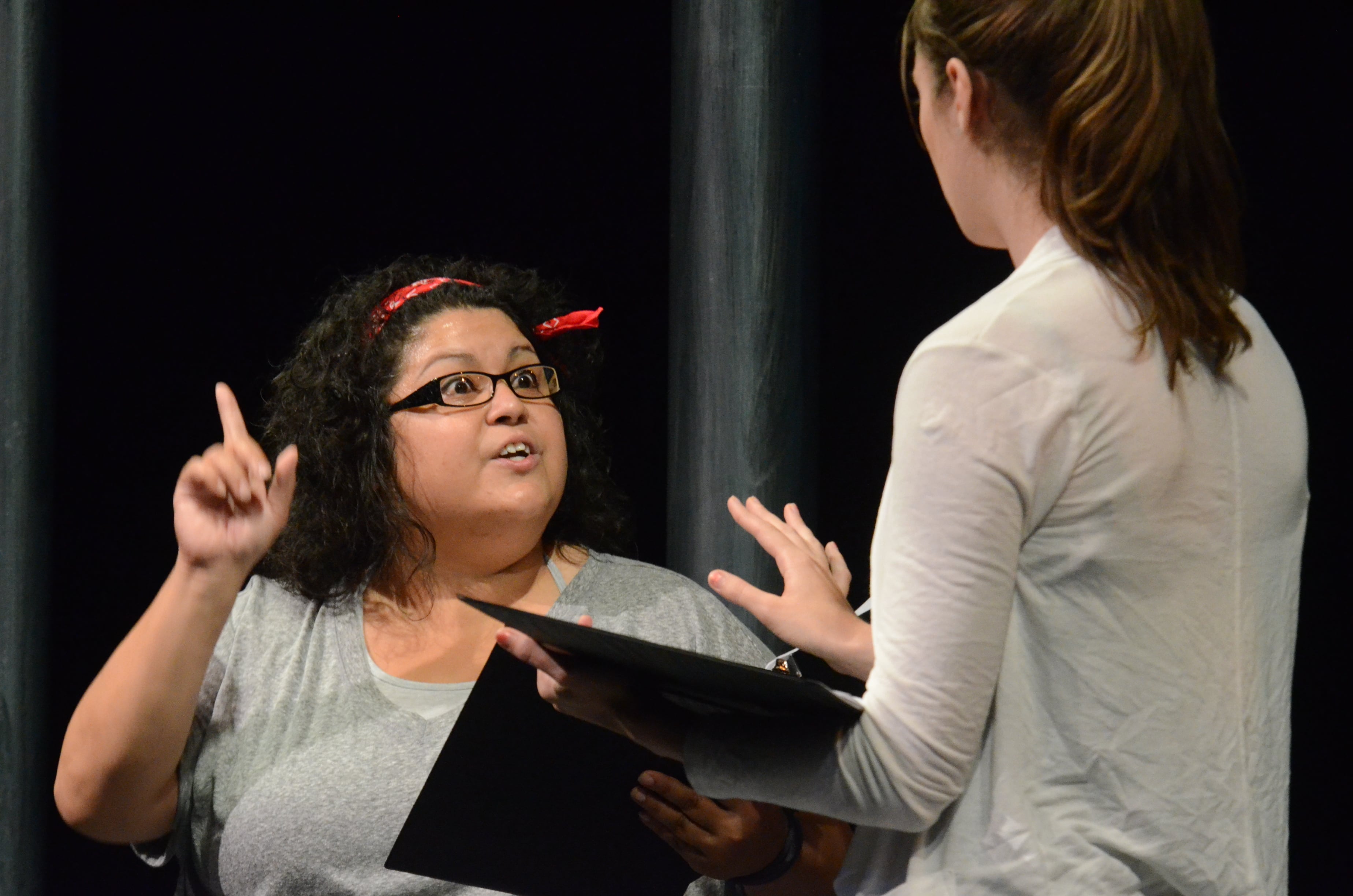 Two actors rehearse lines from scripts they are holding in their hands.