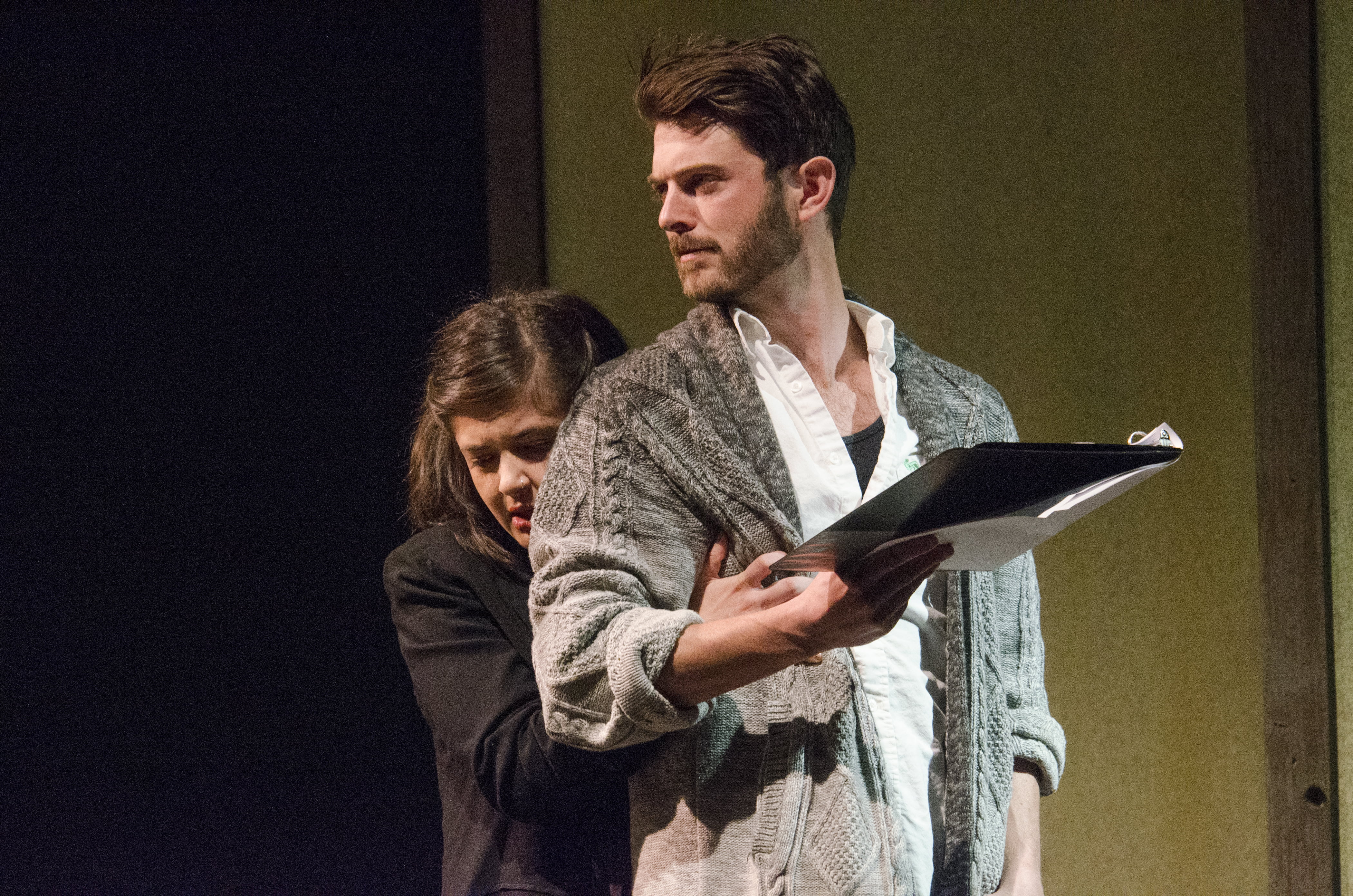 Two actors rehearse lines from scripts they are holding in their hands.