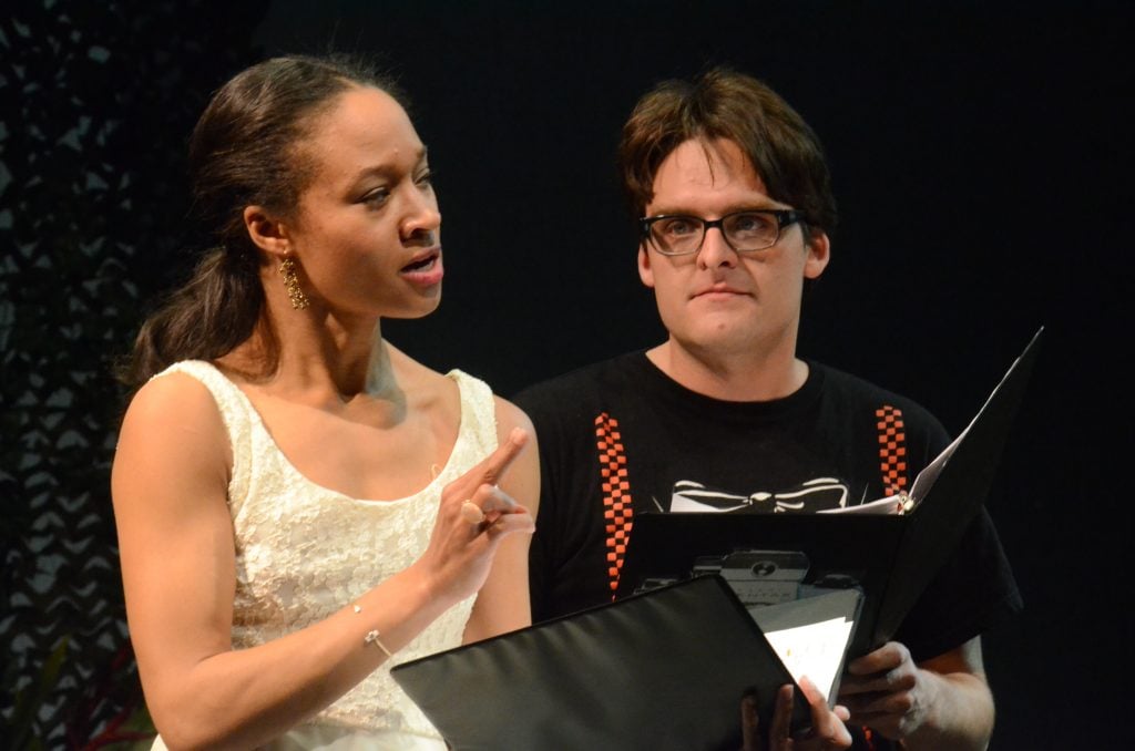 Two actors rehearse lines from scripts they are holding in their hands.