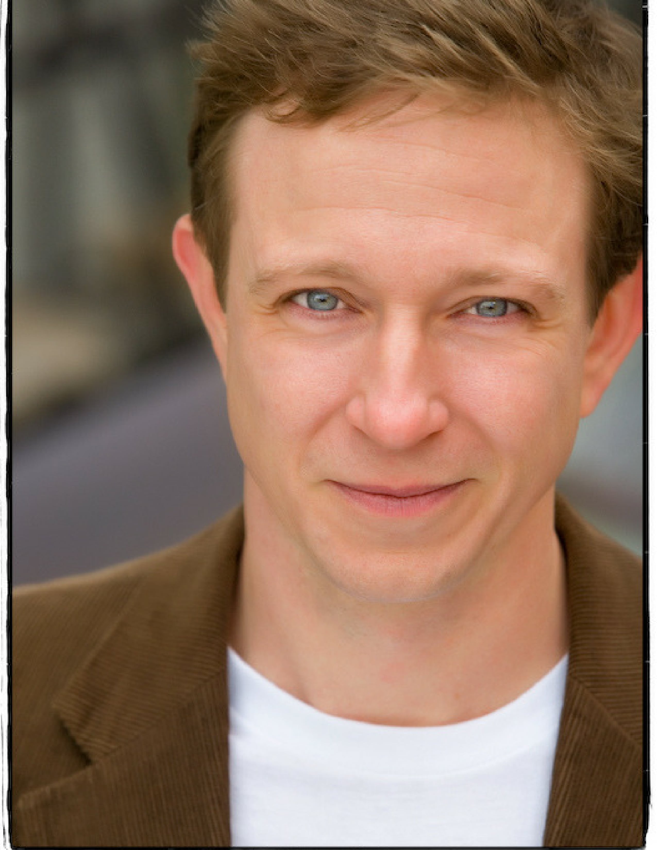 An actor smiles for his headshot photo.